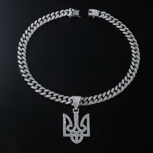 Macro detail of silver hip hop necklace with iced out trident pendant on black background