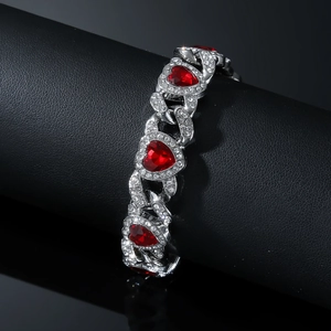 Macro detail of silver Cuban link bracelet with iced-out crystals and red heart gems