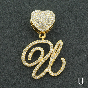 Macro shot of iced-out letter U pendant with golden heart buckle and paved crystals