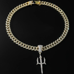 Detailed view of gold Cuban chain and trident pendant with sparkling pavé crystals