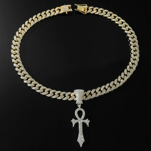 Gros plan d'une chaîne cubaine plaquée or et d'un pendentif croix Ankh serti de diamants