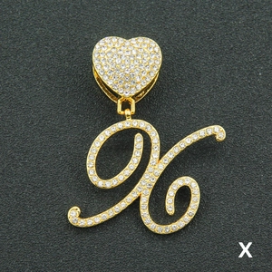 Macro detail of iced-out gold letter X pendant with heart clasp and sparkling crystals