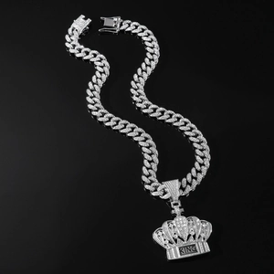 Macro shot of hip-hop iced out crown pendant with KING letters on a silver Cuban chain