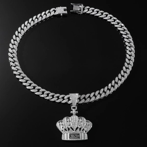 Macro shot of silver hip-hop crown pendant with KING letters on iced out Cuban chain