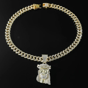 Detailansicht der goldenen Panzerkette mit Jesus-Anhänger und Strass auf schwarzem Spiegel