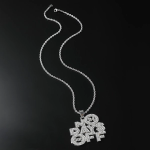 Macro shot of silver rope chain and iced-out 'NO DAYS OFF 24/365' hip hop pendant