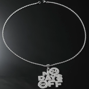 Macro view of iced-out NO DAYS OFF hip-hop pendant with silver rope chain detail