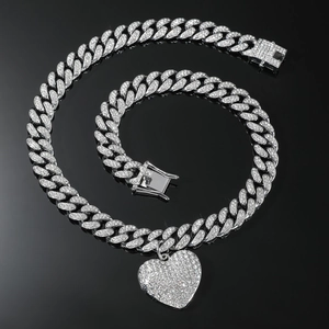 Detailopname van zilveren Cubaanse schakelketting met hartvormige hanger vol met zirkonia
