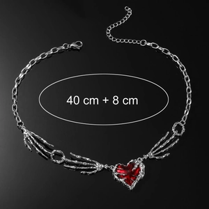 Collier punk main squelette avec pendentif cœur rouge et chaîne argentée sur fond noir
