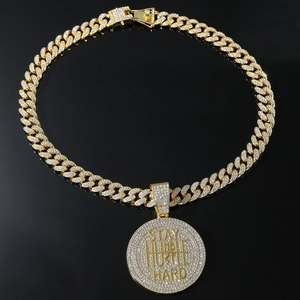 Macro view of gold iced-out Cuban chain and Stay Humble Hustle Hard pendant detail