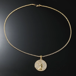 Détail d'un pendentif Néfertiti plaqué or serti de strass sur une chaîne de corde