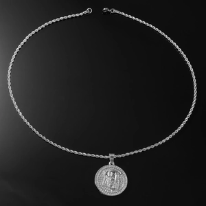 Macro detail of silver tone Jesus pendant with sparkling pavé stones and rope chain