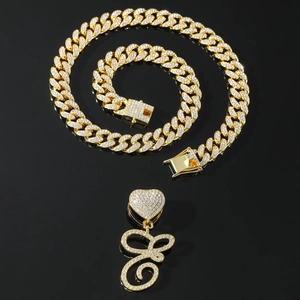 Hip hop style gold Cuban link chain with a large iced out heart and letter E pendant
