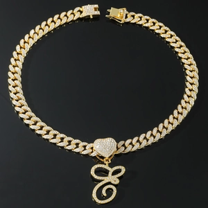 Macro shot of gold Cuban link chain with iced out heart and letter G pendant