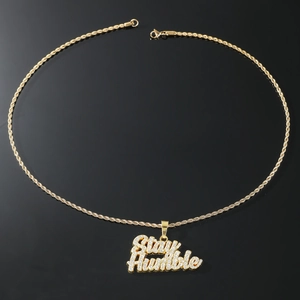 Details des goldenen Stay Humble Anhängers mit glitzernden Strasssteinen und Kordelkette
