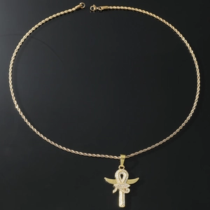 Macro detail of gold Ankh cross pendant with wings and rope chain on reflective black surface