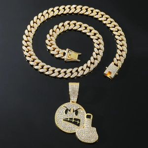 Hip-hop emoji pendant with full rhinestones on golden Cuban link chain over black background