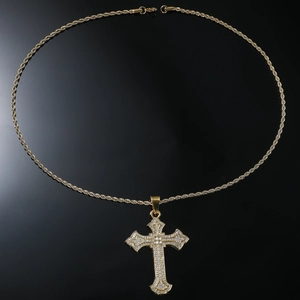 Macro detail of gold hip hop cross pendant with paved zircon stones on rope chain