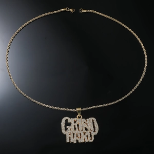 Macro shot of gold hip hop necklace featuring iced out GRIND HARD letter pendant detail