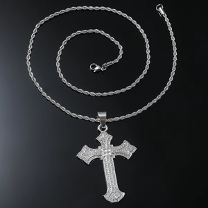 Macro shot of silver hip-hop cross pendant with iced-out diamonds on a black rope chain