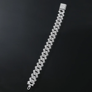 Détail macro du bracelet à maillons cubains argentés sertis de strass brillants sur fond noir
