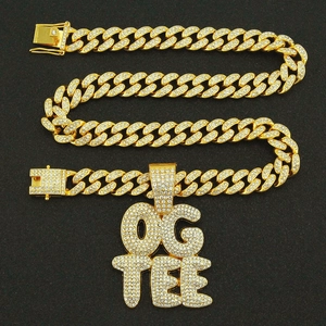 Détail de la chaîne cubaine dorée avec pendentif OG TEE et strass brillants style hip hop