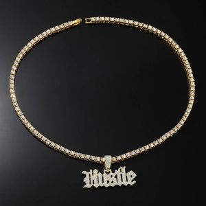Vue détaillée du pendentif Hustle doré avec zircons blancs sur une chaîne tennis