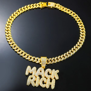 Close-up of gold iced out Mack Rich letter pendant on a heavy Cuban link chain