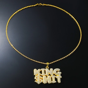 Detailed view of hip hop KING SHIT pendant with iced out crystals and gold rope chain
