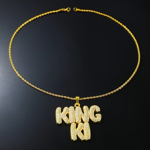 Détail de la chaîne torsadée dorée et pendentif lettres KING KI avec strass brillants