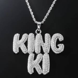 Vue rapprochée d'un collier hip-hop argenté avec pendentif KING KI serti sur chaîne corde