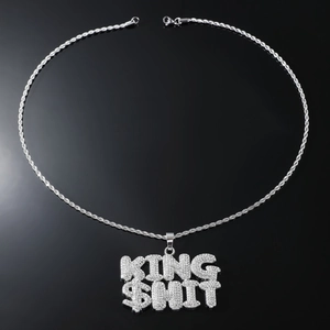 Macro shot of silver hip-hop necklace with iced-out KING $HIT letter pendant and rope chain