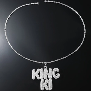 Vue macro du pendentif Hip-Hop KING KI argenté avec strass sur chaîne cordelette