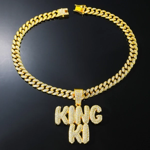 Macro view of gold-plated hip hop King Ki pendant with cubic zirconia on Cuban link chain