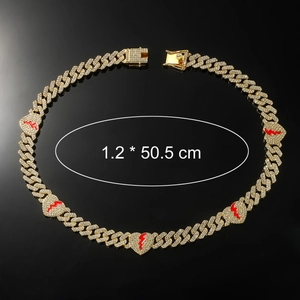 Macro detail of gold Cuban chain with red enamel broken hearts and inlaid crystals