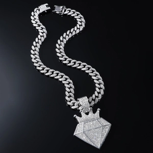 Hip-hop silver Cuban chain with a large iced-out crown diamond pendant on black background