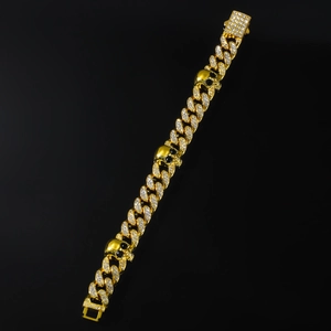 Macro detail of gold-plated Cuban link bracelet featuring skull motifs and pave crystals