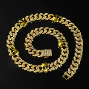 Détail du collier punk à mailles cubaines dorées avec crânes glacés et yeux en pierre noire
