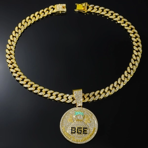 Détail macro du pendentif BGE doré serti de strass et grosse chaîne cubaine à fermoir