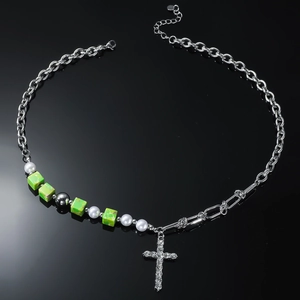 Chic green beaded cross necklace with silver chains and pearls on a black reflective surface