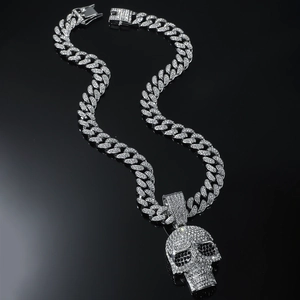 Macro detail of iced-out hip hop skull pendant with silver Cuban chain and clear crystals