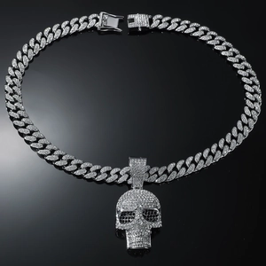 Macro shot of iced out skull pendant and sparkling Cuban link chain on dark surface