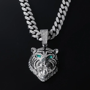 Detailed close-up of a silver-toned hip hop lion pendant with green eyes and Cuban link