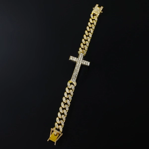 Macro detail of gold Cuban link bracelet with iced-out cross and sparkling zircons