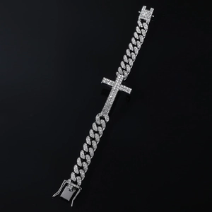 Macro shot of silver hip-hop Cuban link bracelet with iced-out cross and crystal pave