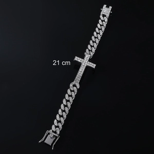 Macro detail of 21 cm iced-out cuban link bracelet with a sparkling cross pendant
