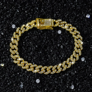 Macro shot of gold-tone iced-out Cuban link necklace with rhinestones on black background