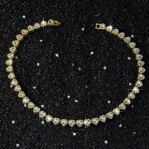 Detailed macro view of a 10mm golden heart link necklace with sparkling crystals on black stone