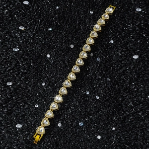 Macro shot of gold-plated 10mm heart links with iced-out crystals on a textured dark background