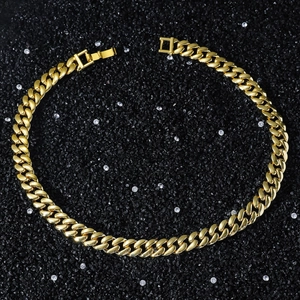 Detail of 12mm gold Cuban link chain with secure fold-over clasp on black stone background
